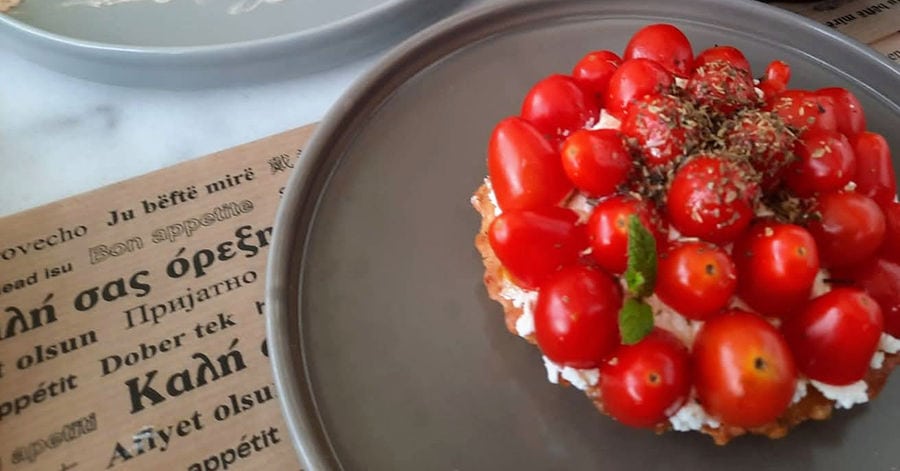 A picture of ntakos shows a Cretan dish consisting of a thick slice of barley rusk topped with chopped tomatoes and feta cheese